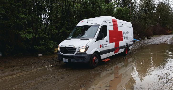 red cross van driving through flooding street